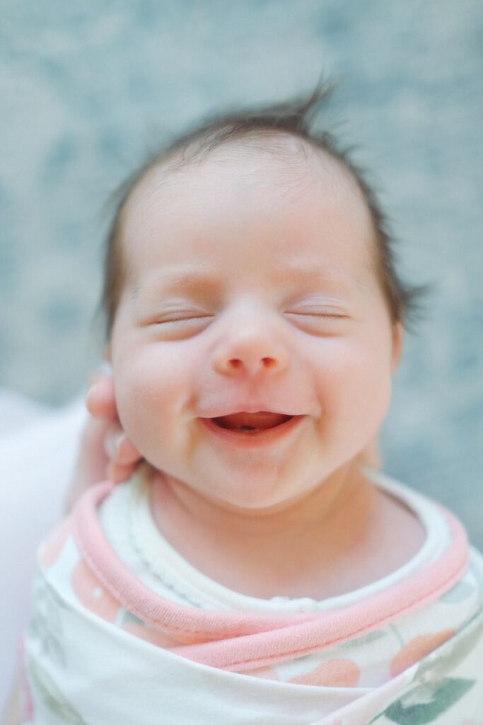 a close up of a baby smiling with its eyes closed