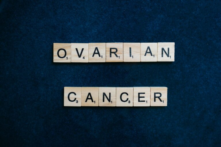 Scrabble tiles spelling 'Ovarian Cancer' on dark background, promoting awareness.